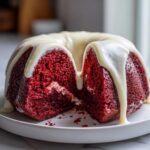 Close-up of a sliced red velvet bundt cake drizzled with thick white cream cheese glaze.