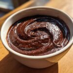 Close-up of thick, rich homemade chocolate pudding swirled beautifully in a small white bowl.