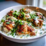 Close-up of seared coconut lime chicken pieces swimming in a rich, creamy sauce and topped with fresh cilantro.