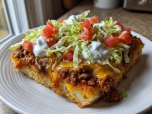 A thick slice of taco pizza topped with seasoned ground beef, melted cheese, lettuce, tomatoes, and sour cream.