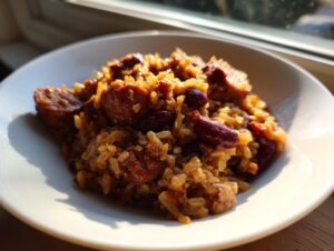 A close-up of a white bowl filled with flavorful slow cooker red beans and rice mixed with sliced sausage.