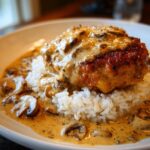 Close-up of smothered chicken and rice topped with creamy mushroom gravy.