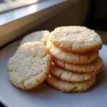A stack of golden, round butter cookie treats generously topped with coarse sugar crystals.