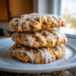 Close-up of three stacked, chewy iced oatmeal cookies drizzled with white vanilla glaze.