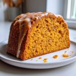 A close-up of a moist slice of sweet potato pound cake topped with a thick caramel glaze.