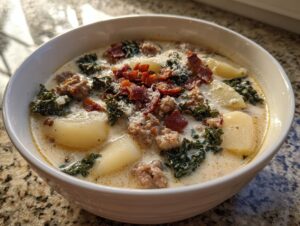 A close-up of a hearty bowl of Zuppa Toscana soup with sausage, potatoes, kale, and bacon.