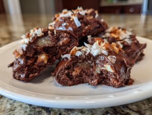Close-up of a halved almond joy cookie showing the gooey caramel, coconut, and chocolate layers.