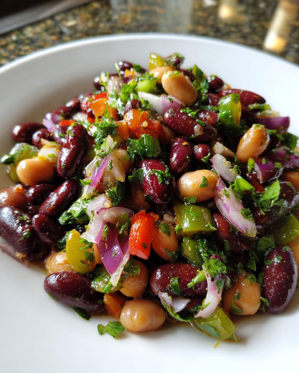 Close-up of a vibrant, mixed bean salad featuring kidney beans, cannellini beans, red onion, green pepper, and fresh parsley.