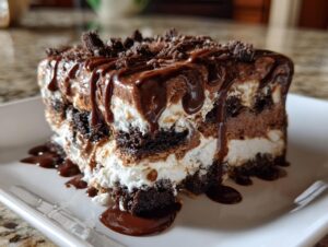 A rich, layered slice of Baileys Chocolate Cheesecake Trifle topped with chocolate sauce and cookie crumbs.