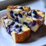 Two stacked slices of moist blueberry french toast casserole showing creamy filling and baked blueberries.