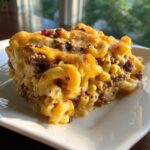 A close-up serving of rich cheeseburger casserole featuring elbow macaroni, ground beef, and melted cheddar cheese.