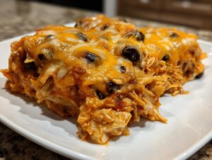 A close-up of a hearty serving of burrito bake, featuring shredded chicken, sauce, black beans, and melted cheddar and Monterey Jack cheese.