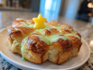 A close-up of freshly baked Christmas tree cinnamon rolls drizzled with light green icing and topped with a yellow star.