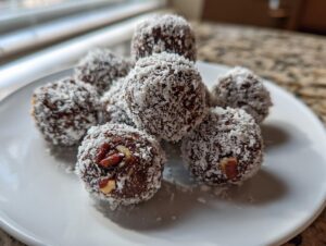 A cluster of homemade bourbon balls rolled in shredded coconut, served on a white plate.