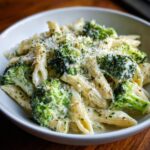 Close-up of creamy broccoli pasta featuring penne, bright green florets, and grated Parmesan cheese.