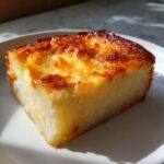 A square slice of creamy cassava cake with a beautifully caramelized, golden-brown top, resting on a white plate.