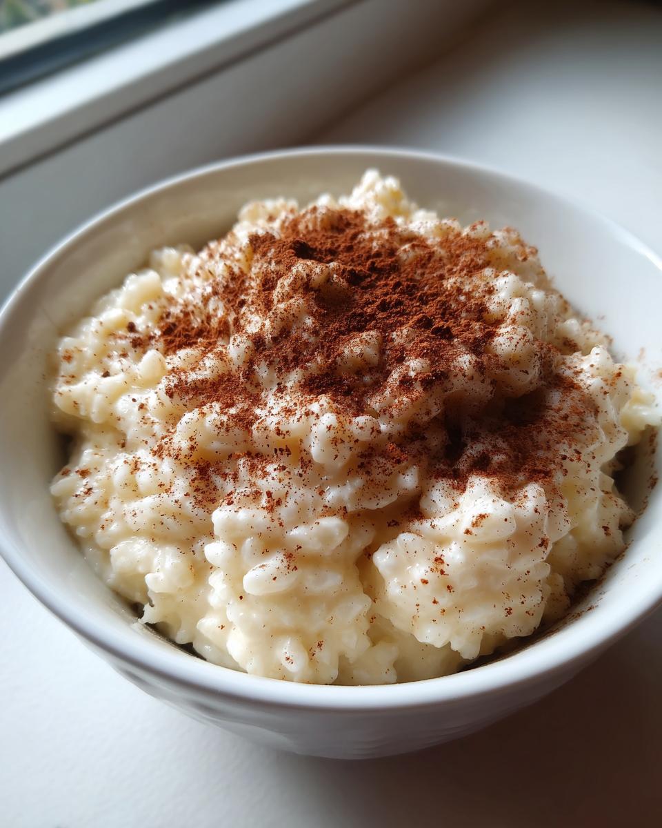 Close-up of creamy rice pudding served in a white bowl and generously dusted with cinnamon powder.