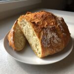 A freshly baked Italian bread loaf, cut in half to show the soft interior and golden, crusty exterior.