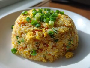 A mound of golden cauliflower rice mixed with scrambled egg and topped with fresh green scallions.