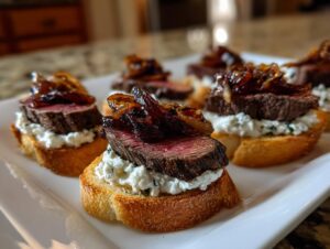 Close-up of several steak crostini appetizers featuring medium-rare steak, creamy cheese, and caramelized onions on toasted bread.