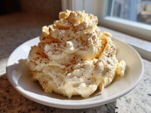 A mound of creamy, whipped honey butter recipe dusted with cinnamon on a white plate.