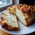 A loaf of freshly baked soda bread, cut open to show the soft interior and golden crust.