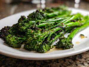 Close-up of perfectly cooked, slightly charred garlic lemon broccolini served on a white plate.