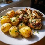 Close-up of perfectly roasted garlic parmesan chicken and potatoes, sprinkled with parsley and cheese.