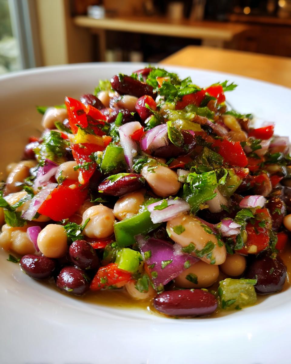 Close-up of a vibrant, colorful bean salad featuring kidney beans, chickpeas, red onion, peppers, and fresh herbs.