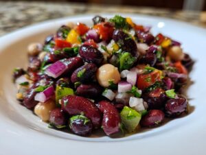Close-up of a vibrant, fresh bean salad featuring kidney beans, chickpeas, red onion, and herbs.