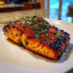 A perfectly cooked, glazed salmon fillet topped with fresh parsley, ready to eat.