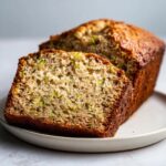 A close-up of a moist slice of banana zucchini bread showing the texture and green shreds of zucchini.