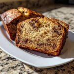 Close-up of moist slices of vegan banana bread loaded with chocolate chips on a white plate.