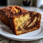 Close-up of a slice of snickerdoodle zucchini bread showing a rich cinnamon swirl pattern inside.