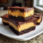 Close-up of stacked buckeye brownies showing the dark chocolate base, thick peanut butter layer, and chocolate topping.