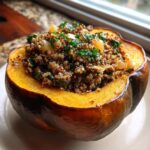 A close-up of a baked stuffed acorn squash filled with a savory quinoa mixture and topped with fresh parsley.