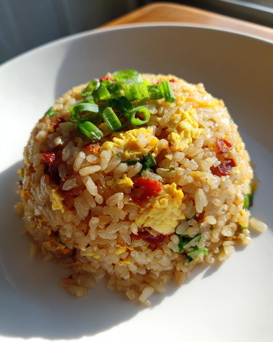 A mound of savory cauliflower rice mixed with scrambled egg and topped with fresh green onions, mimicking takeout style.