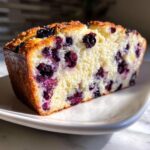 A close-up slice of fluffy blueberry cloud cottage cheese bread showing moist crumb and dark blueberries.