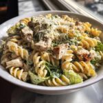 A close-up of cheddar's chicken caesar pasta salad featuring rotini pasta, grilled chicken, and creamy dressing.
