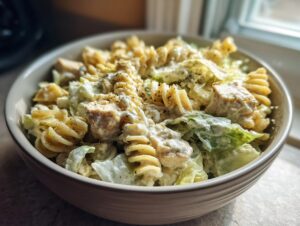 Close-up of Cheddar's Chicken Caesar Pasta Salad featuring rotini pasta, chicken chunks, romaine lettuce, and creamy dressing.