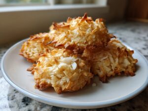 A stack of golden brown, crispy coconut cookies easy macaroons piled on a light blue-rimmed white plate.