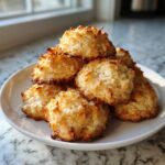 A stack of golden brown, textured coconut cookies easy to make, piled on a white plate.
