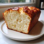 A thick slice of fluffy cottage cheese bread showing its soft interior and golden-brown crust, served on a white plate.