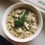 A close-up overhead view of a bowl of creamy chicken wild rice soup garnished with fresh parsley.