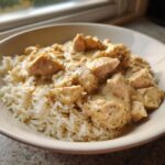 Close-up of creamy crockpot chicken and rice served in a light-colored bowl.