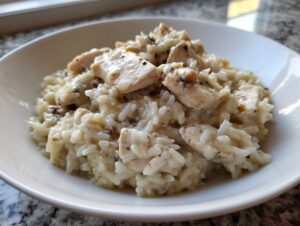 Close-up of creamy crockpot chicken and rice served in a white bowl, seasoned with pepper.