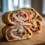 Two stacked slices of delicious italian pinwheels 12 tomatoes recipe, showing layers of ham, cheese, and red peppers.
