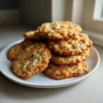 A tempting stack of freshly baked oatmeal coconut cookies piled high on a small white plate.