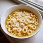 Close-up of a white bowl filled with pastina soup italian penicillin, topped generously with grated Parmesan cheese and black pepper.