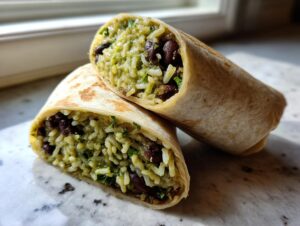 Close-up of a black bean and rice burrito cut in half, showing the green-tinted rice and black beans inside.